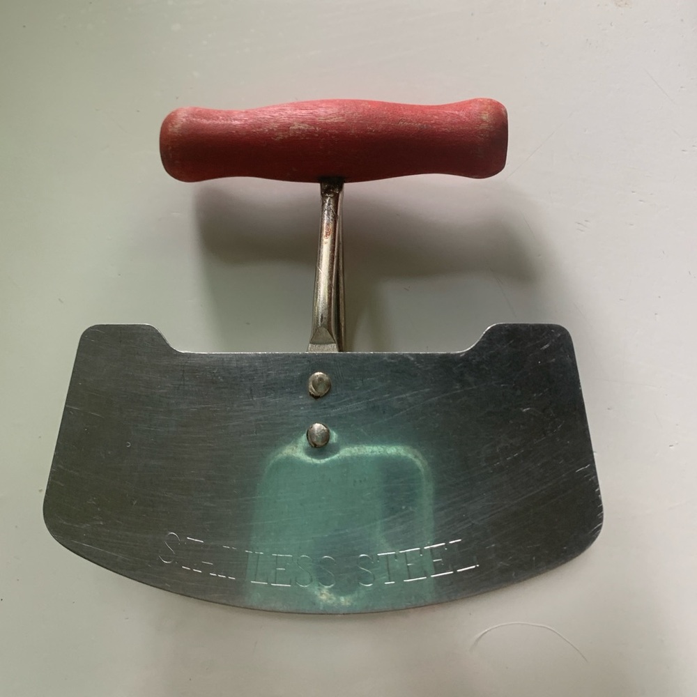 Stainless steel chopper or dough cutter with red handle.